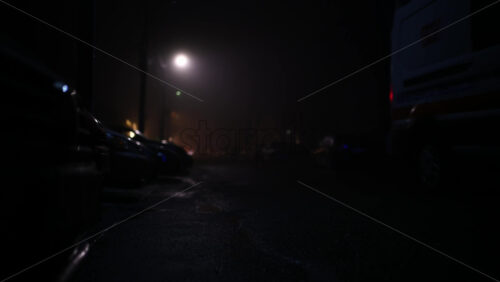 Low angle view of an emergency vehicle approaching along a dark, wet street at night