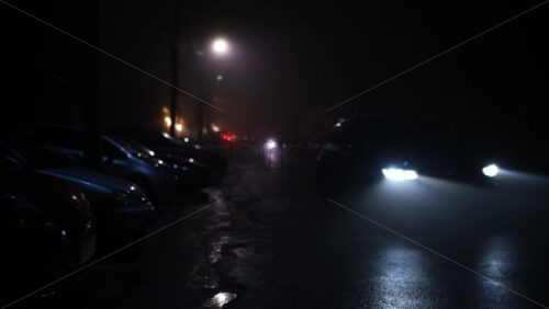 Car driving slowly toward the camera on a foggy city street at night
