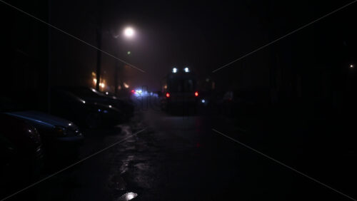 Car driving slowly toward the camera on a foggy city street at night