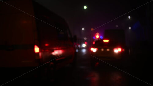 Rear view of an ambulance driving through traffic on a city street at night