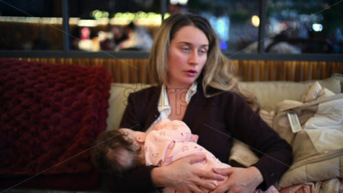 Mother sitting on a sofa while gently holding and looking at her newborn baby