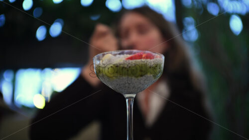 Woman eating a chia pudding dessert with fresh fruit toppings