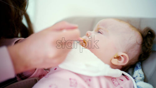 Close up of a baby being gently fed with a spoon by an adult