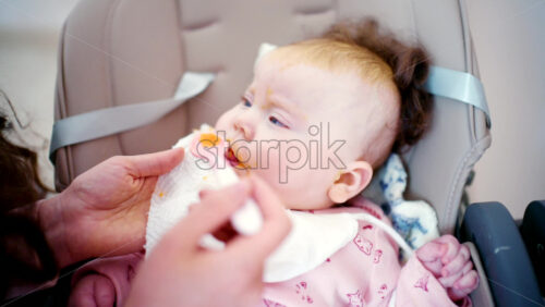 Close up of a baby being gently fed with a spoon by an adult