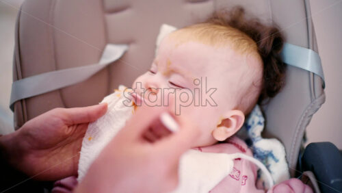 Close up of a baby being gently fed with a spoon by an adult