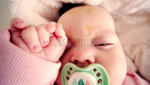 Close up of a newborn baby sleeping peacefully while sucking on a pacifier