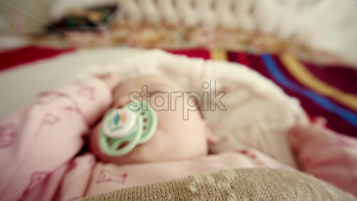 Close up of a newborn baby sleeping peacefully while sucking on a pacifier
