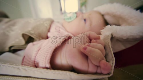 Side view of a newborn baby sleeping in a padded stroller, covered with a warm blanket