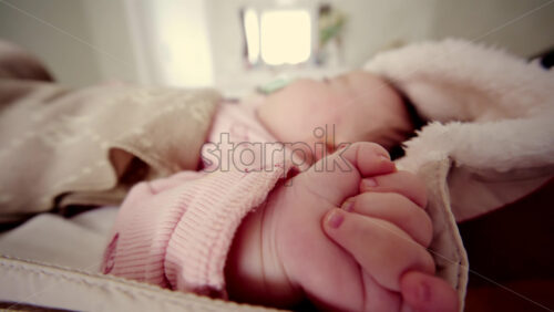 Side view of a newborn baby sleeping in a padded stroller, covered with a warm blanket