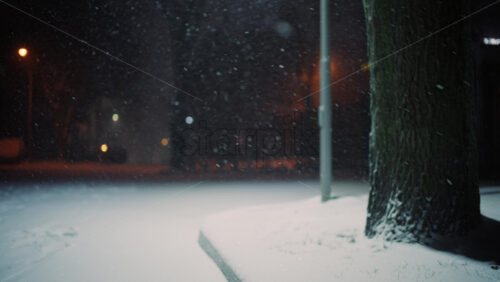 Close up of snow covered ground with shallow depth of field as snowflakes fall gently