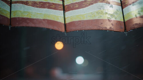 Close up view of snowflakes falling beneath a striped awning at night