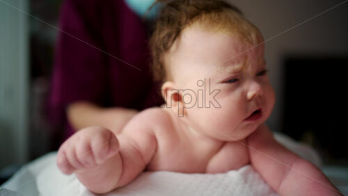 Adult hands gently supporting a baby's head and neck during tummy time