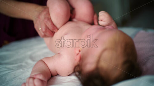 Baby lying on their back while an adult massages them and gently holds the baby's hand