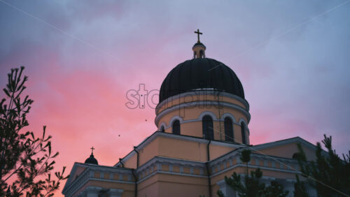 Chisinau, Moldova - January 10, 2026: Exterior view of the Nativity Cathedral topped with a cross against a soft pink and blue sunset sky