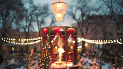 Wide view of a festive Christmas decoration with lights, at an outdoor cafe near small trees, and ornaments