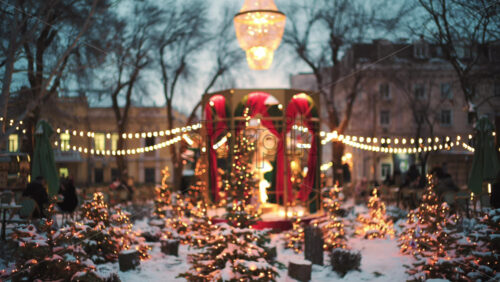 Wide view of a festive Christmas decoration with lights, at an outdoor cafe near small trees, and ornaments