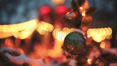 Close up of a round Christmas ball ornament hanging on a snow covered evergreen branch