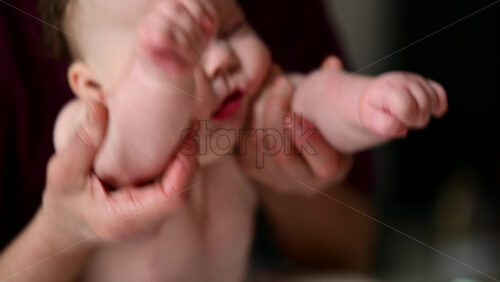 Cute baby lying on stomach during tummy time while interacting with a pacifier