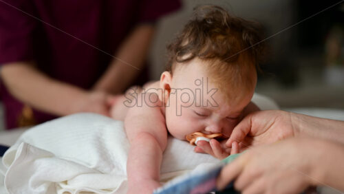 Cute baby lying on stomach during tummy time while interacting with a pacifier