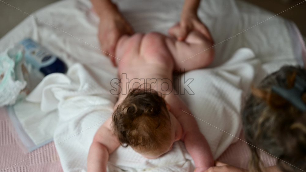 Tender moment of a baby holding an adult's hand while receiving a gentle massage