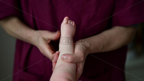 Close up of adult hands gently massaging a baby's foot and sole