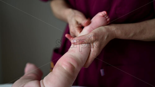 Close up of adult hands gently massaging a baby's foot and sole