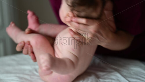 Caregiver gently lifting and supporting a baby during a massage and care routine