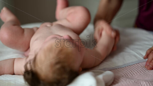 Close up of adult hands gently massaging a baby's arm and palm