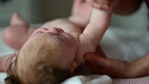 Close up of adult hands gently massaging a baby's arm and palm