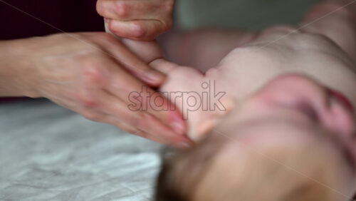 Close up of adult hands gently massaging a baby's arm and palm