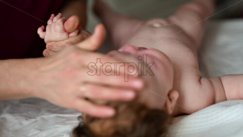 Close up of adult hands gently massaging a baby's arm and palm