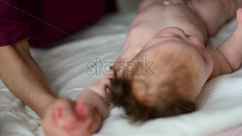 Close up of adult hands gently massaging a baby's arm and palm