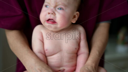 Baby sitting upright while being supported by a caregiver from behind