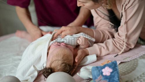 Mother gently wrapping a baby in a soft blanket during a massage and care session