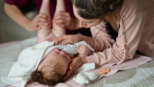 Mother gently wrapping a baby in a soft blanket during a massage and care session