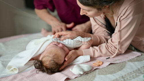 Mother gently wrapping a baby in a soft blanket during a massage and care session