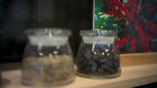 Row of glass jars filled with different coffee beans displayed on a wooden shelf