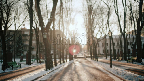Out of focus view of people walking along a snowy park path during sunset