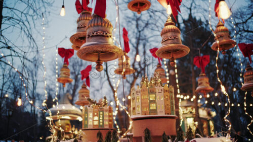 Decorative Christmas bells hanging above a festive market display with warm fairy lights and red bows