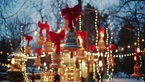 Decorative Christmas bells hanging above a festive market display with warm fairy lights and red bows