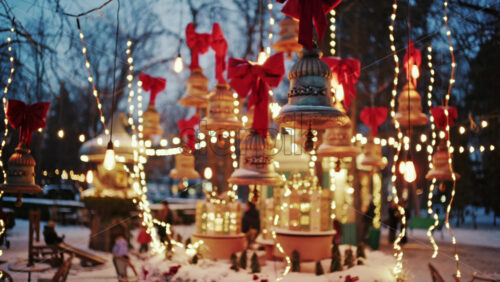 Decorative Christmas bells hanging above a festive market display with warm fairy lights and red bows