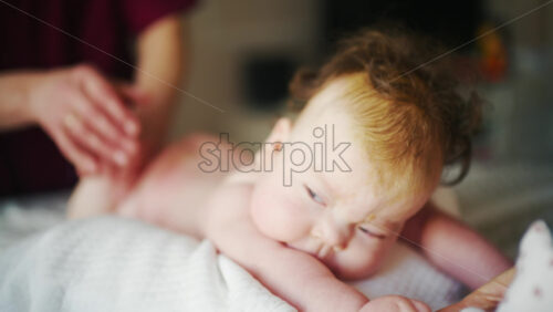 Baby lying comfortably while grasping an adult's finger