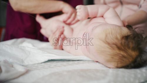 Infant supported by adults while practicing tummy time and doing mobility exercises