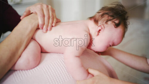 Soft close up of a baby's face while being gently handled by a caregiver on a stability bal