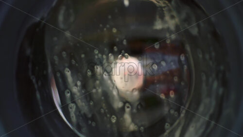Close up view through the glass door of a washing machine during a wash cycle