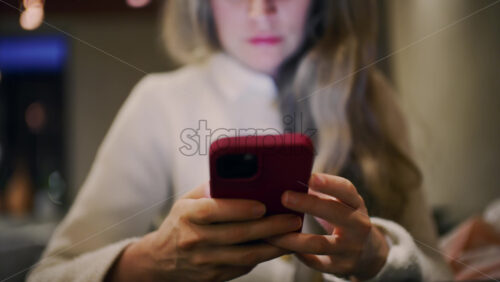 Close up of a woman using a smartphone indoors in soft evening light