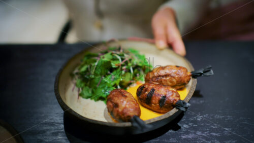 Plate of grilled sausages served with fresh greens and sauce