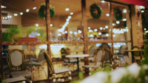 Outdoor restaurant terrace with empty tables and warm interior lighting
