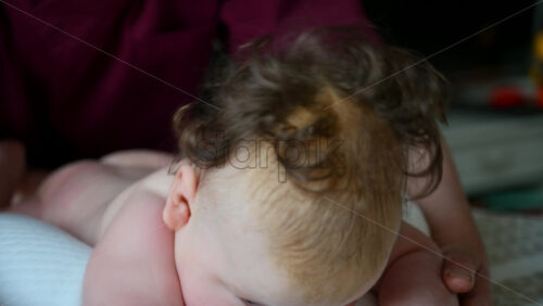 Infant lifting head during tummy time while caregiver supports gently