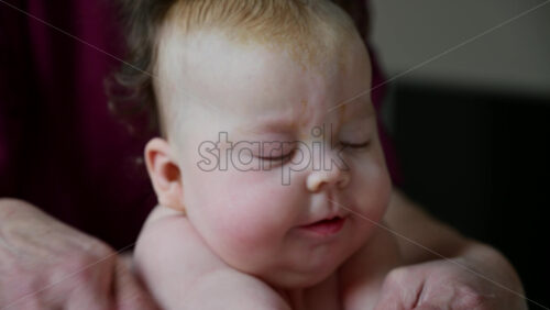 Infant lifting head during tummy time while caregiver supports gently